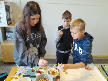 uczniowie stół warzywa przybory kuchenne miski przygotowanie posiłku