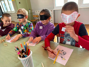 dzieci zakryte oczy stół przybory rysowanie