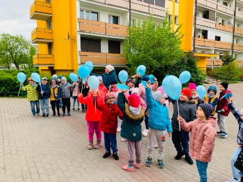 dzieci z niebieskimi balonikami spacerują po osiedlu